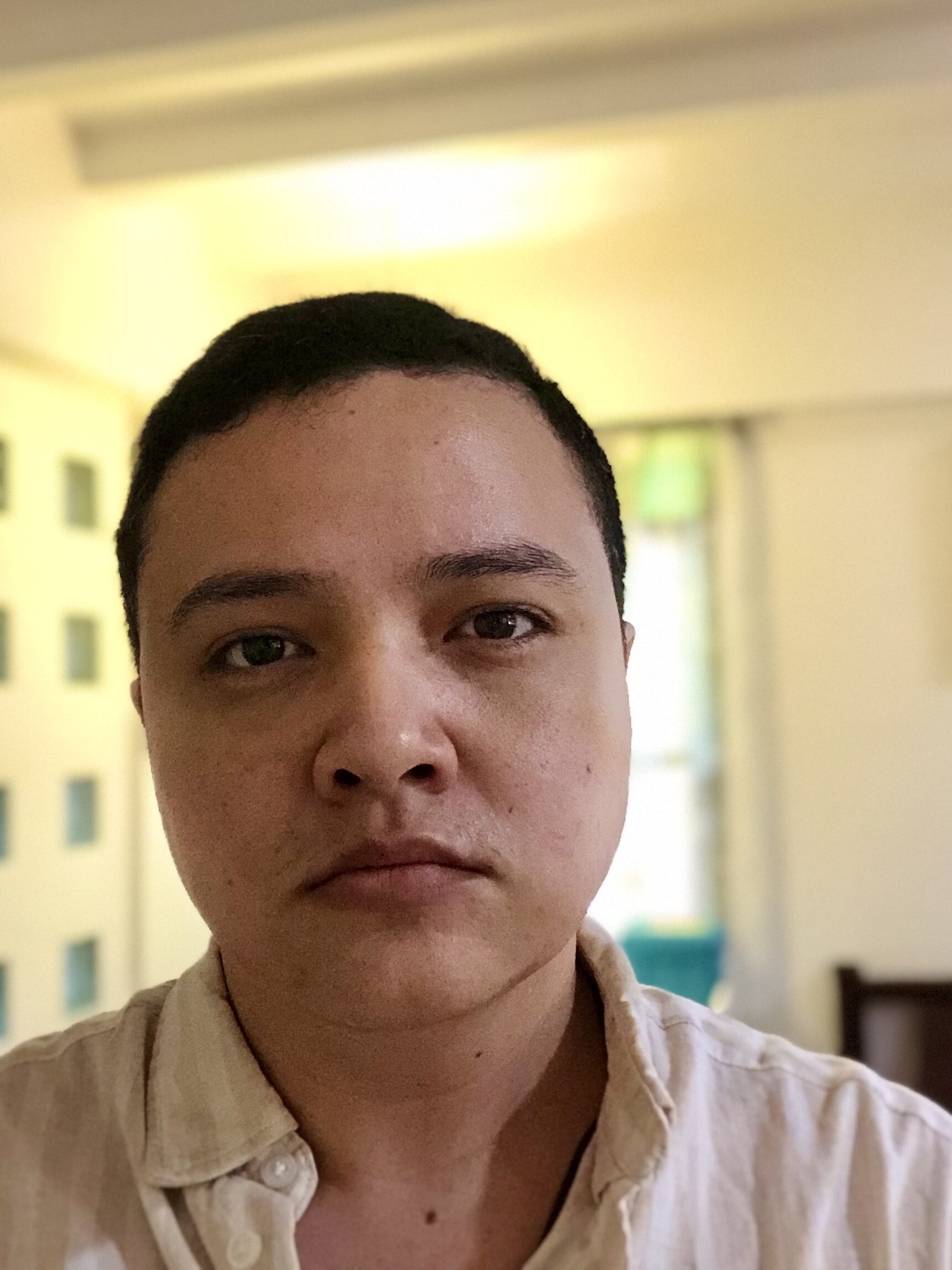 Nico from the collarbones-up. He's wearing a white, linen button-up shirt with the collar undone.